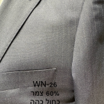 חליפת Adore דגם WN-26 בצבע כחול כהה עם פסים עדינים ו-60% צמר, צילום תקריב של דש הז'קט, כיס החזה ומרקם הבד